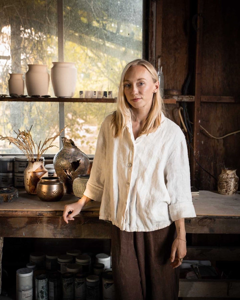 Alex Roby in her studio beside shelves of her pottery