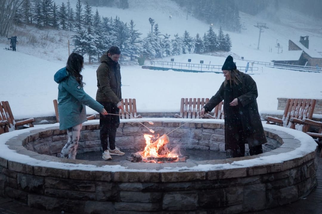 Friends around the fire pit in falling snow at the base of the slopes, Park Hyatt Beaver Creek