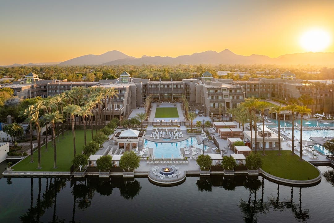 Grand Hyatt Scottsdale across the lake at sunrise, pools and mountains behind