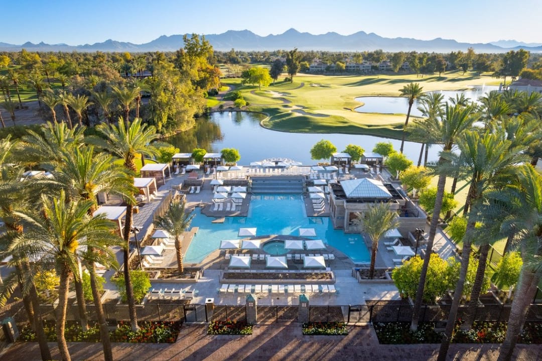 Piscina, cabañas y palmeras de Grand Hyatt Scottsdale desde el aire, con el campo de golf y montañas detrás
