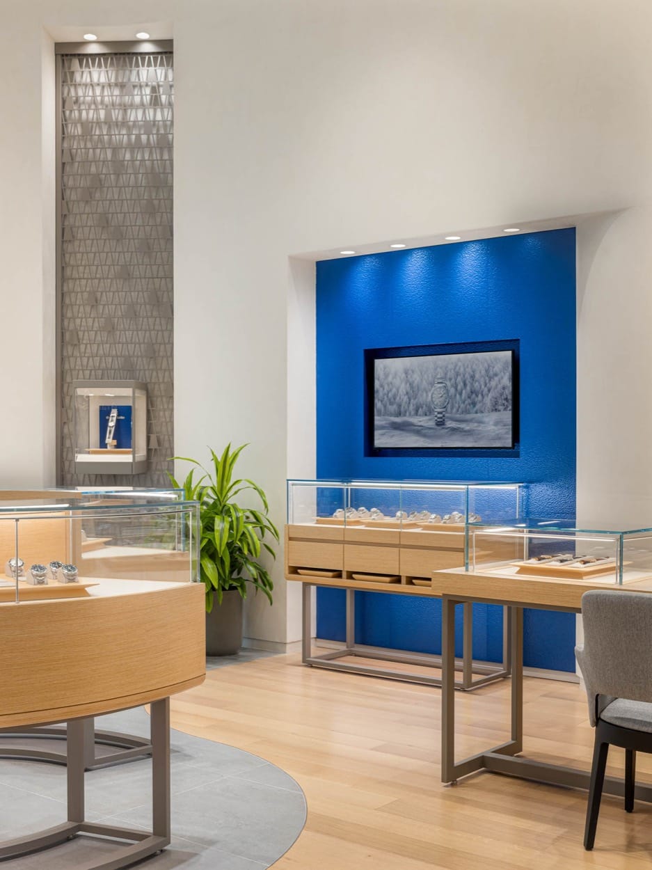 Rincón de la boutique de Grand Seiko, vitrinas de relojes bajo una foto enmarcada en una pared azul
