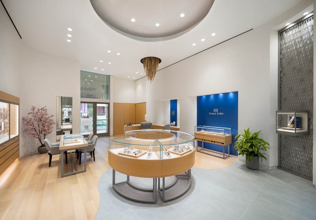 Interior de la boutique de Grand Seiko bajo una lámpara de bronce, con una vitrina redonda al centro