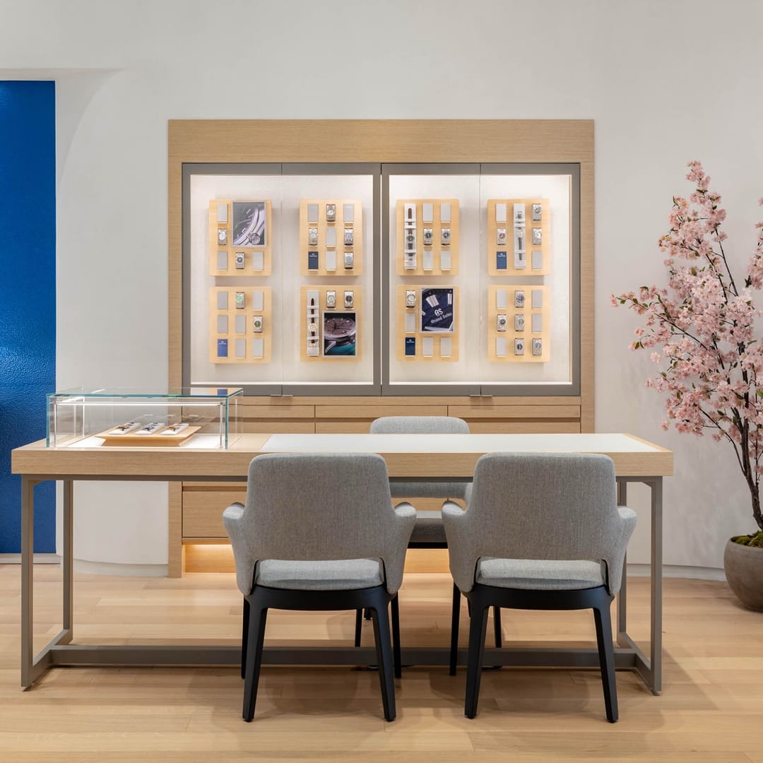 Grand Seiko desk with gray chairs before a wall of watch displays and a blossom branch
