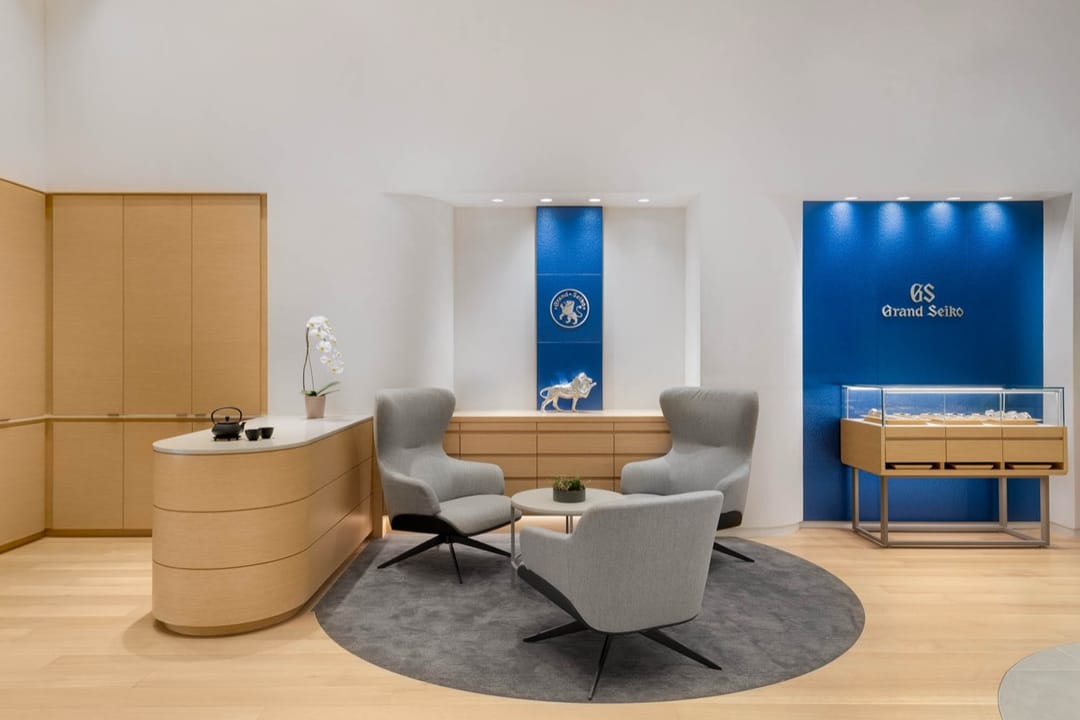 Grand Seiko lounge with gray chairs on a round rug, blue logo walls behind