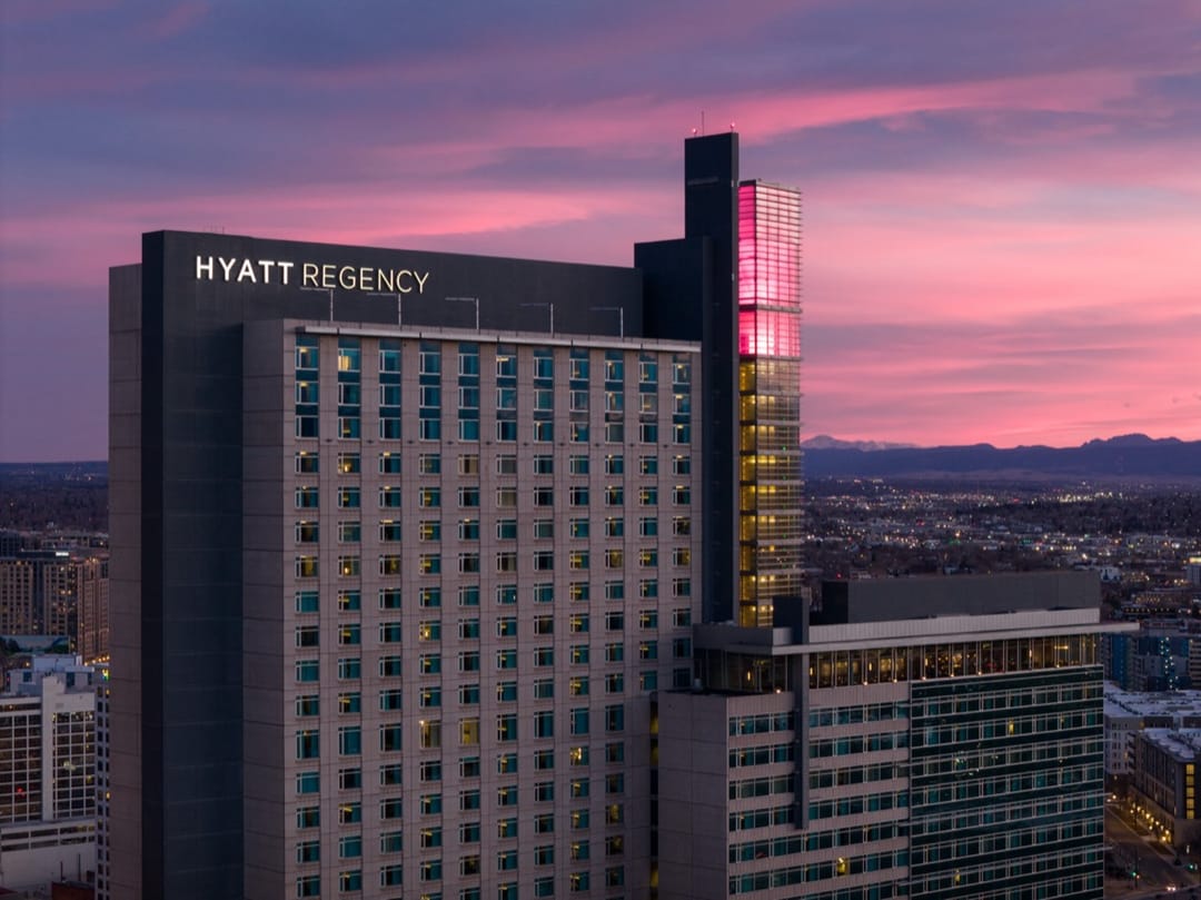 Hyatt Regency Denver al atardecer, cielo rosa sobre la ciudad y las Rocosas en el horizonte