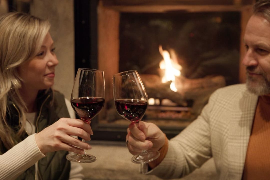 Couple toasting with red wine by the fireplace, Park Hyatt Beaver Creek