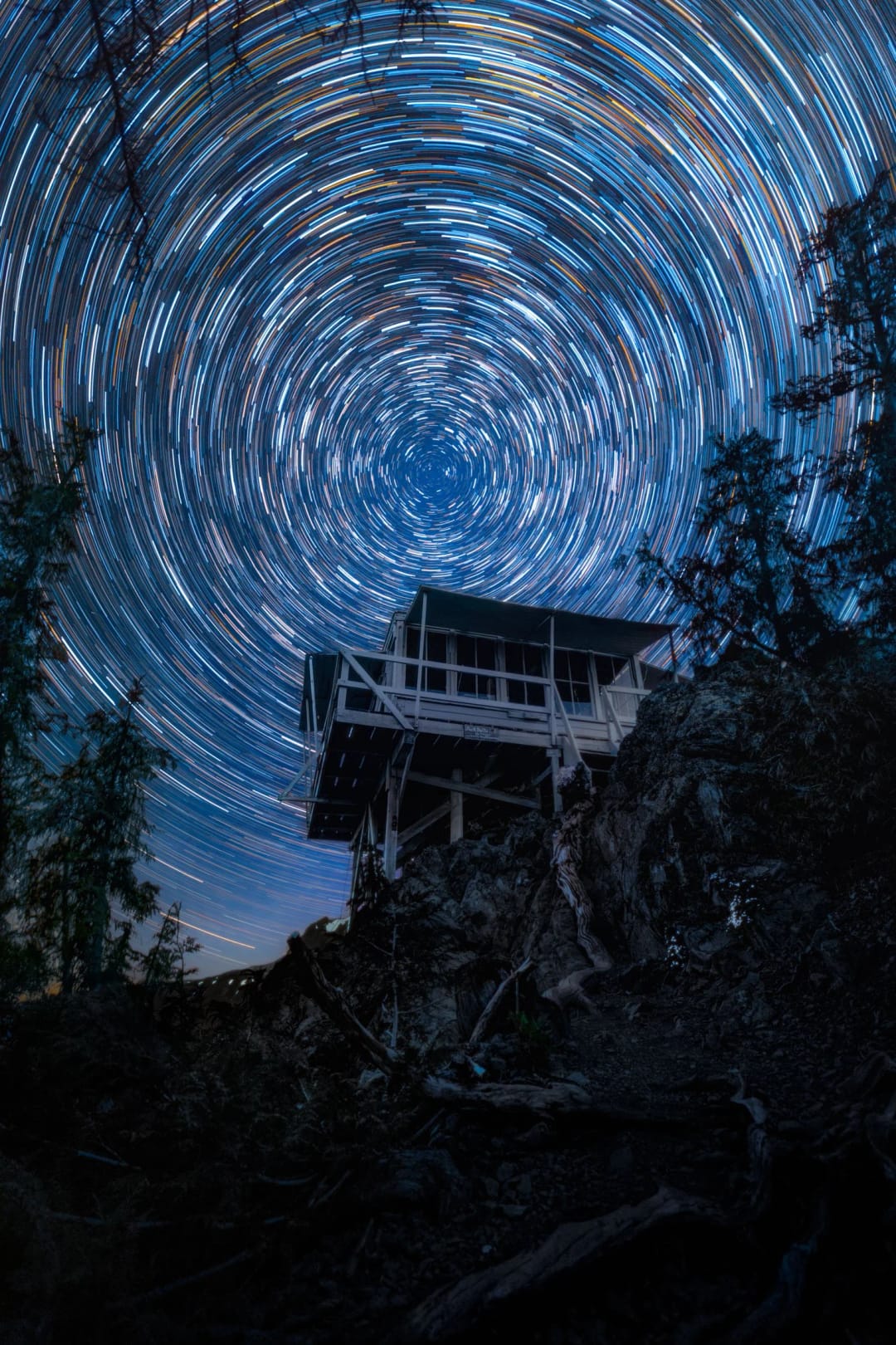 Polaris Lookout. Estelas de estrellas girando alrededor de Polaris sobre una torre de vigilancia entre los árboles