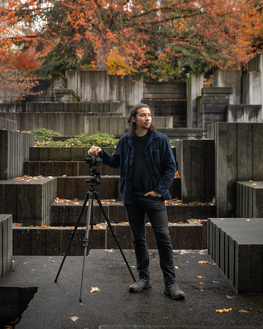 Santiago León with his camera on a tripod among the concrete terraces of Freeway Park in fall