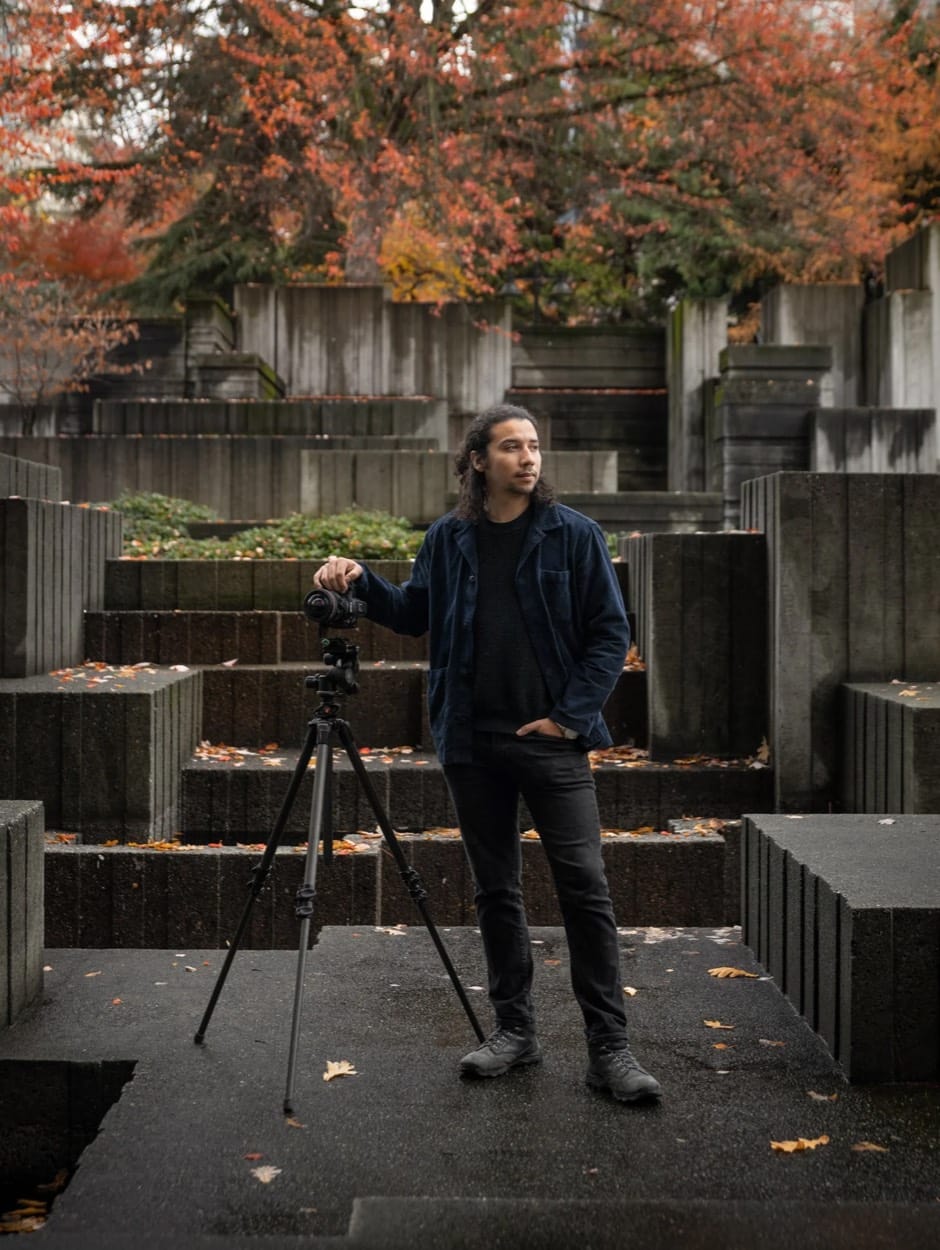 Santiago León, fotógrafo en Seattle, con su cámara en trípode entre terrazas de concreto y hojas de otoño
