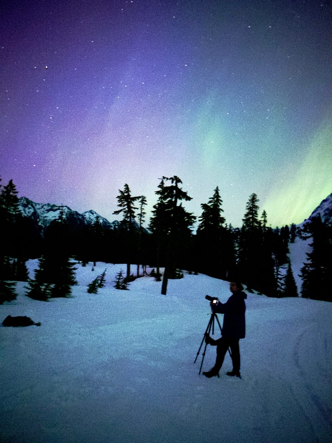 Santiago León with his camera on a tripod in the snow under the aurora, the night of The Substorm of a Generation